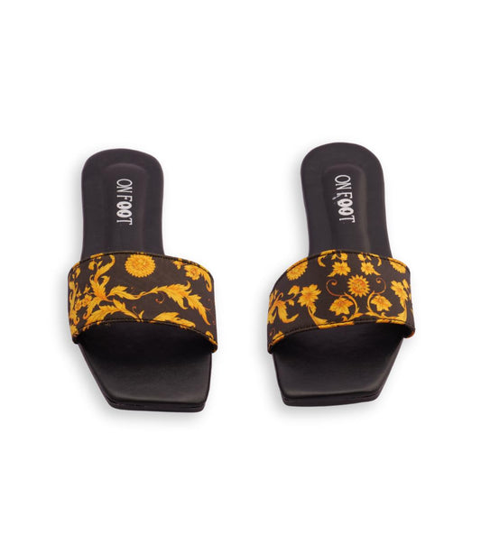 Pair of black slides with yellow floral pattern on a white background