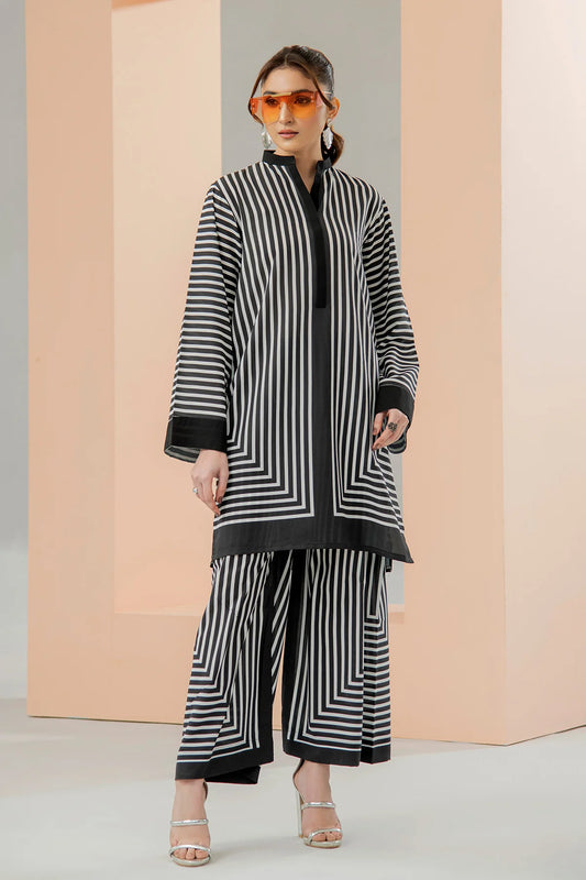 Woman wearing a black and white striped outfit with sunglasses against a neutral background