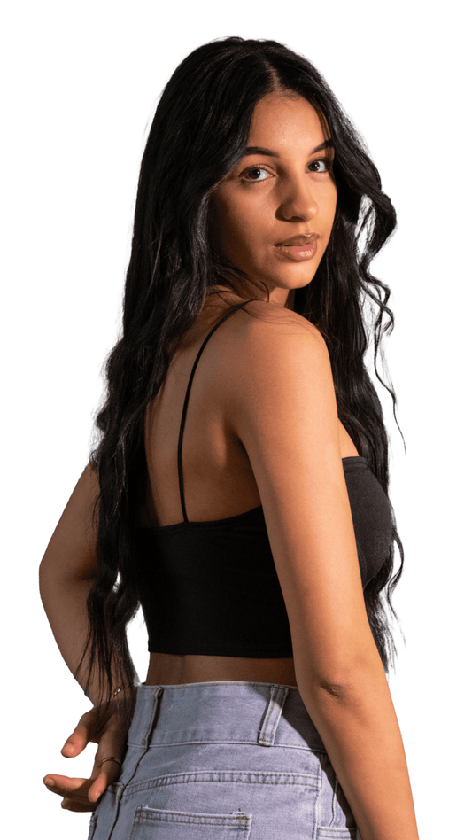 Woman wearing a black crop top and light blue jeans on a white background