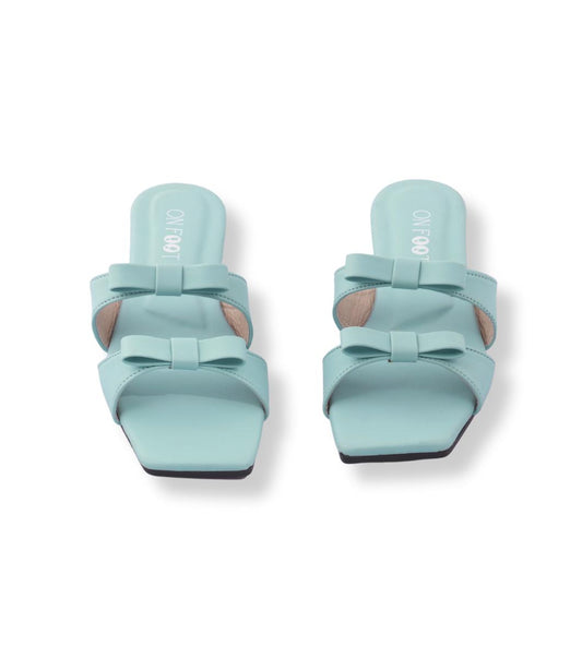 Pair of light blue sandals with bow details on a white background
