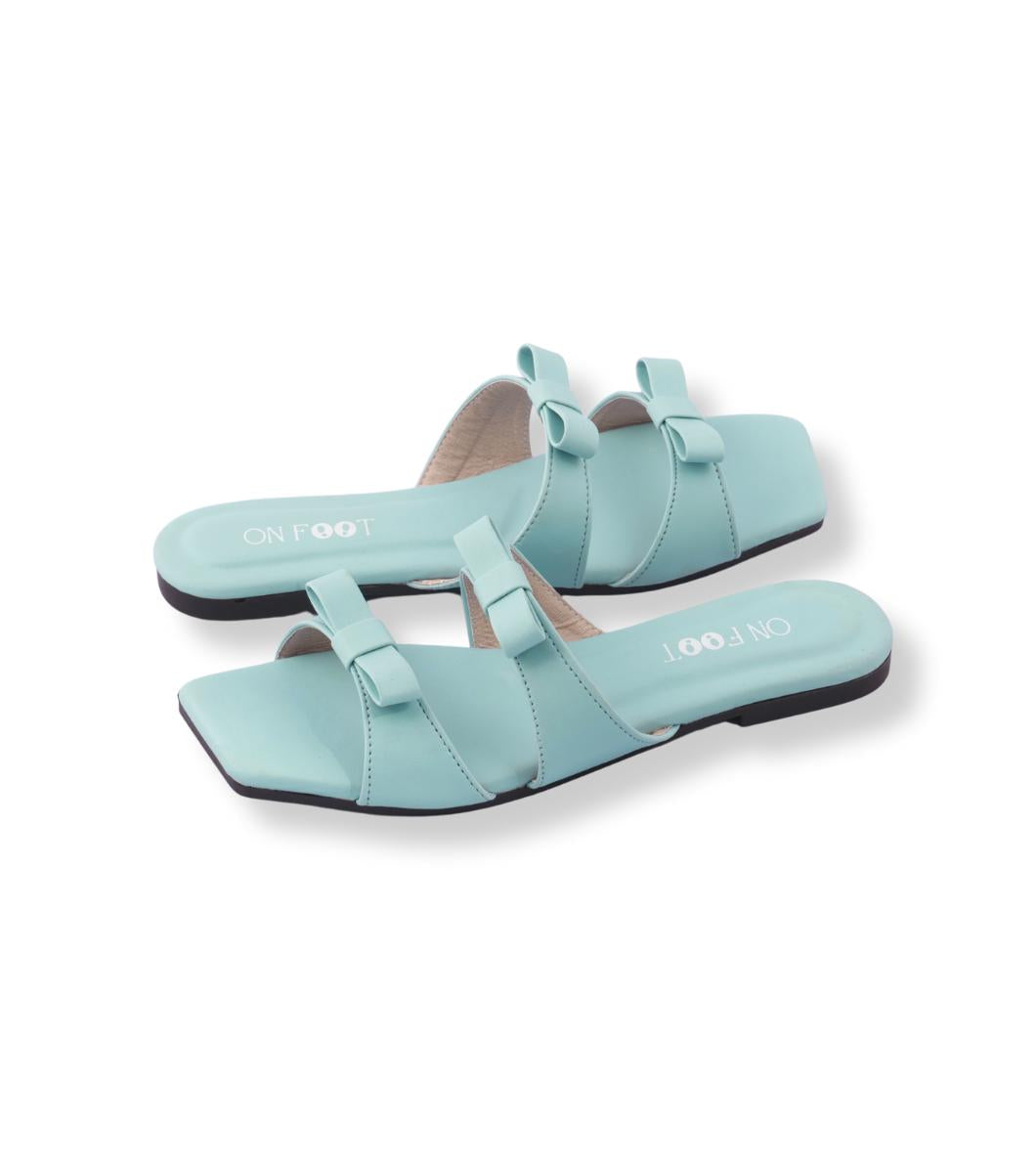 Pair of light blue sandals with bow details on a white background