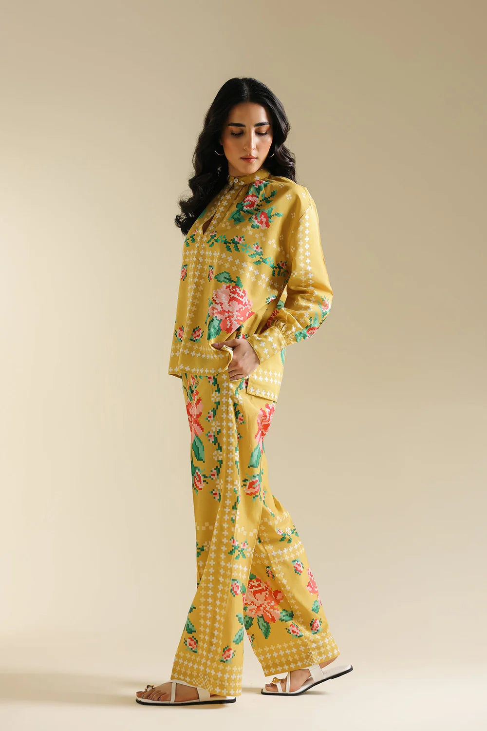 Woman wearing a yellow floral outfit on a beige background