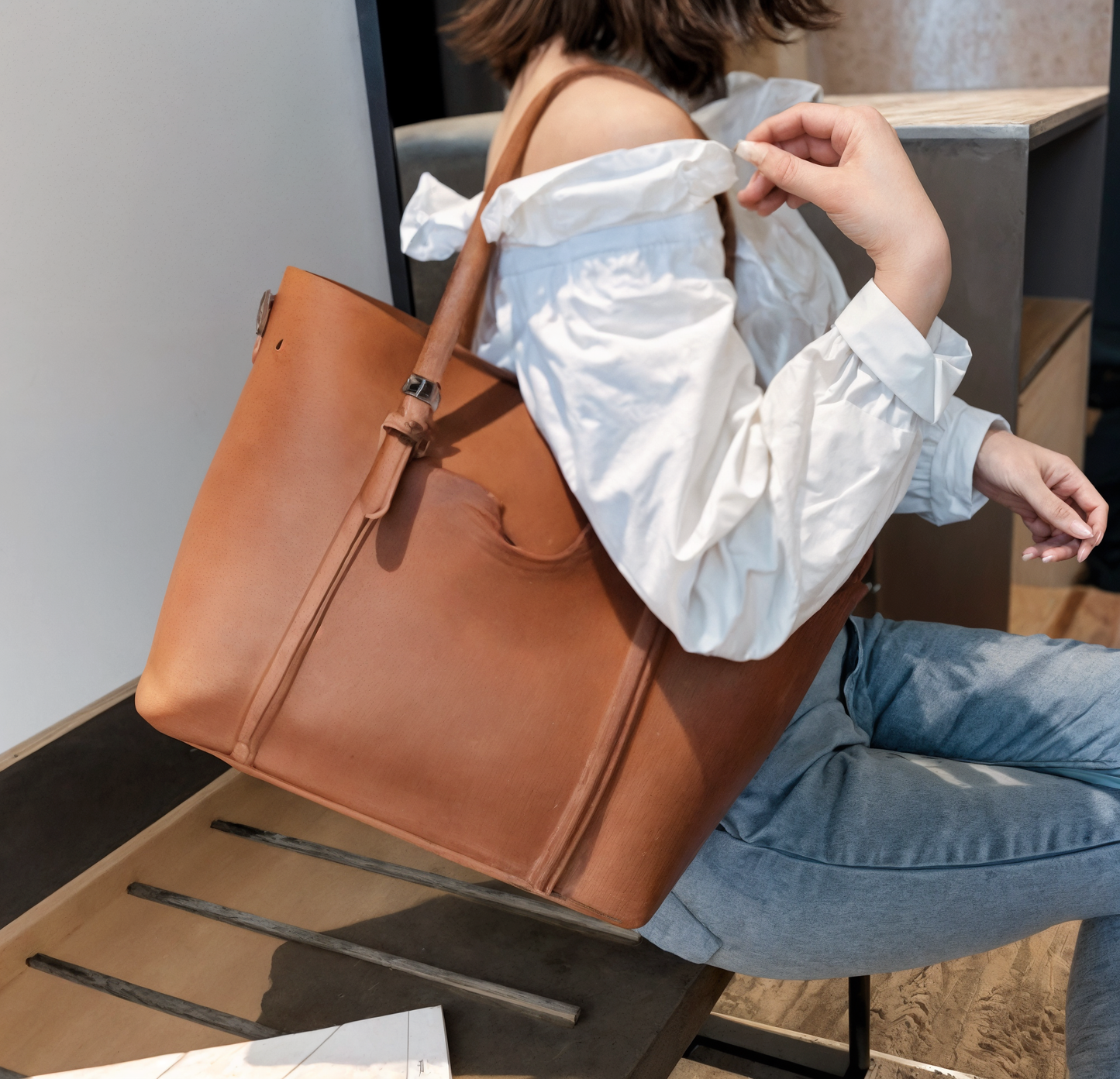 lady holding a brown leather tote bag in an indoor setting