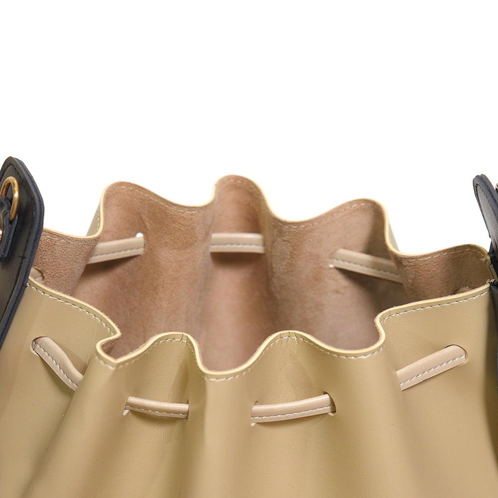 Close-up of a beige leather bag with scalloped edge and stitching details.