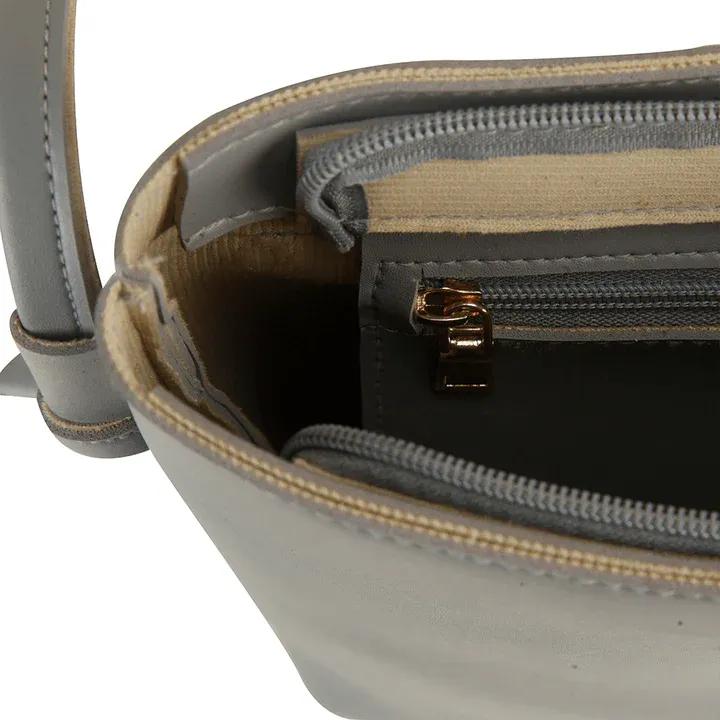 Close-up of a gray handbag with gold zipper and strap.