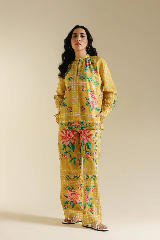 Woman wearing a yellow floral outfit against a beige background