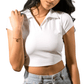 Woman wearing a white cropped polo shirt and light blue jeans on a white background