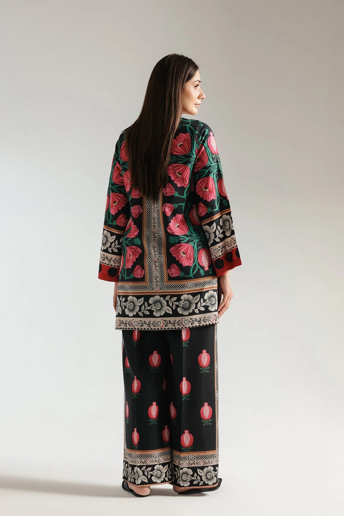 Woman wearing a traditional outfit with floral patterns on a plain background