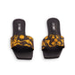 Pair of black slides with yellow floral pattern on a white background