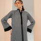 Woman wearing a black and white striped dress with a plain background