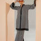 Woman wearing a black and white striped outfit with sunglasses in a minimalistic setting