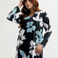 Woman wearing a black floral dress with blue and white flowers on a white background