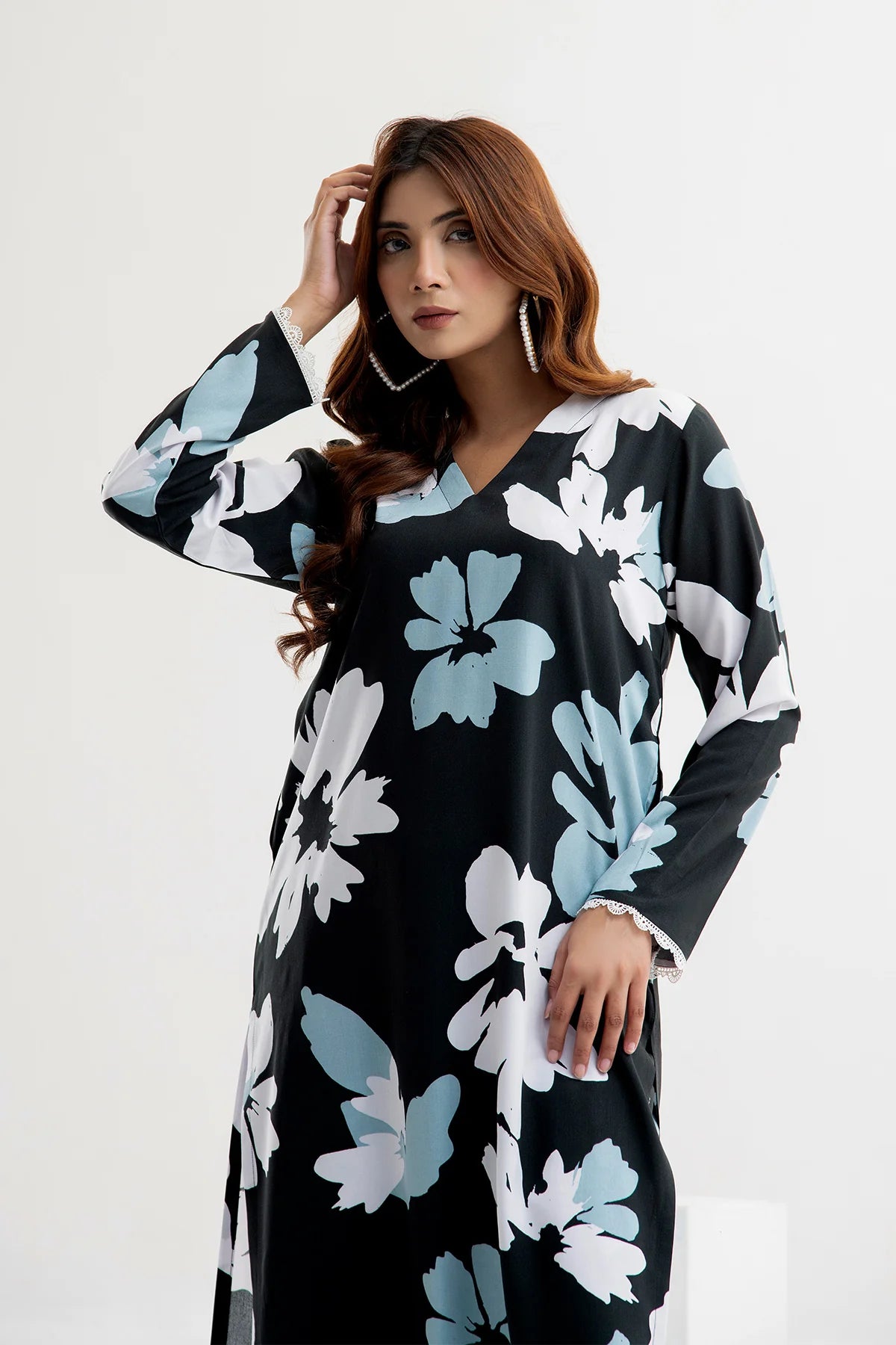 Woman wearing a black floral dress with blue and white flowers on a white background