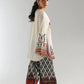 Woman wearing a traditional outfit with embroidered top and pants on a plain background