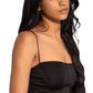 Woman wearing a black strap top and light blue jeans on a white background