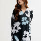 Woman wearing a black floral dress with blue and white flowers on a white background