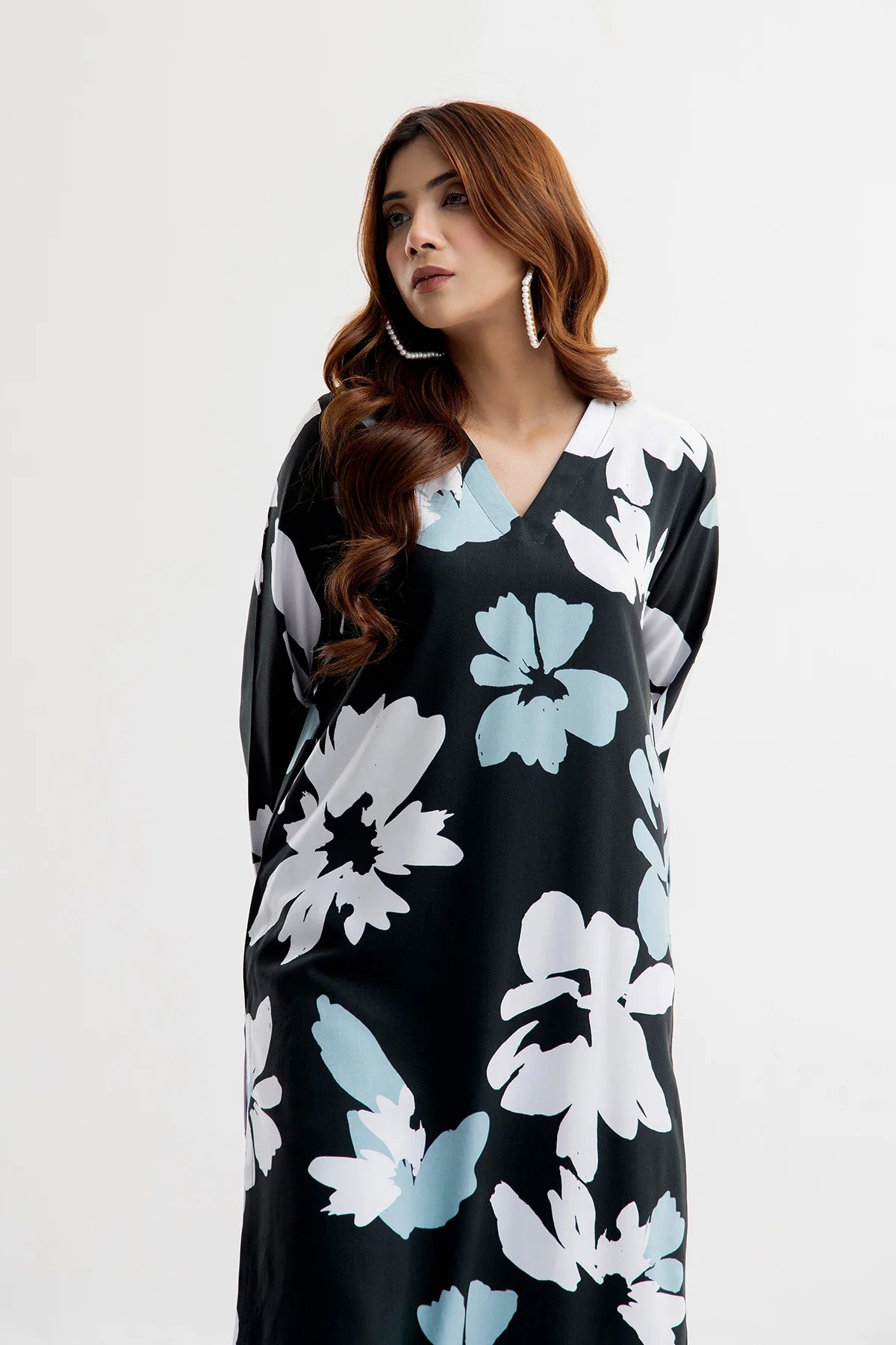 Woman wearing a black floral dress with blue and white flowers on a white background