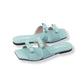 Pair of light blue sandals with bow details on a white background