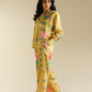 Woman wearing a yellow floral outfit on a beige background