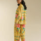 Woman wearing a yellow floral outfit on a beige background