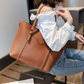 lady holding a brown leather tote bag in an indoor setting