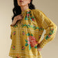 Woman wearing a yellow floral outfit against a beige background