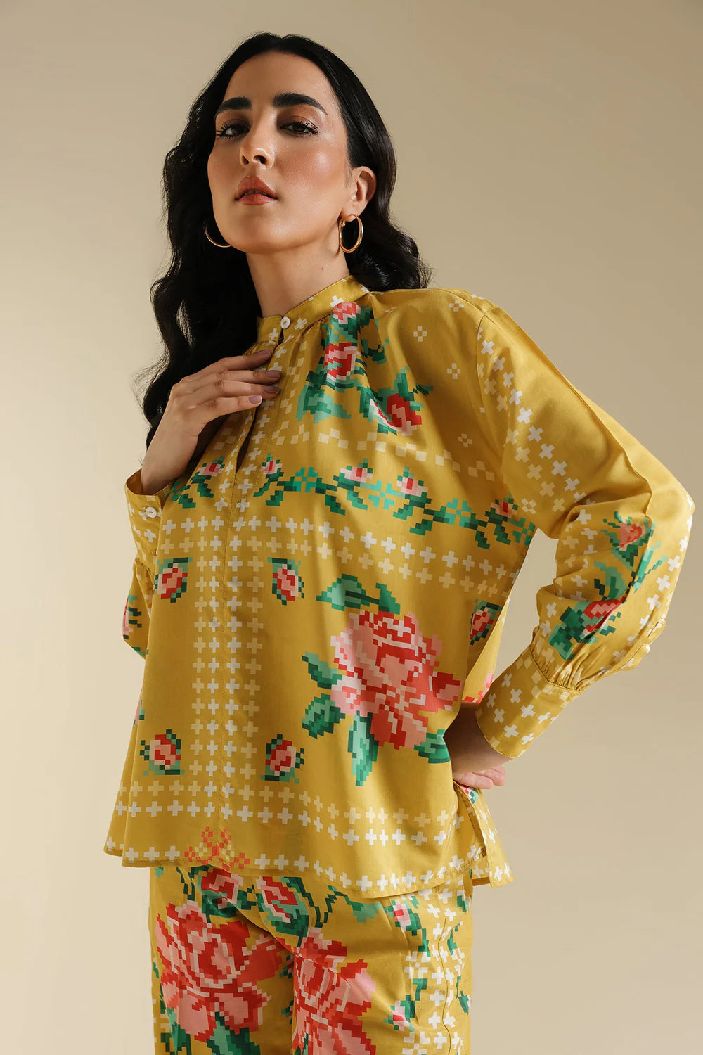 Woman wearing a yellow floral outfit against a beige background