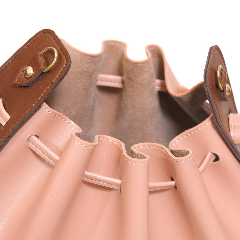 Close-up of a pink leather handbag with brown accents on a white background