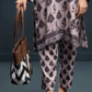 Lady wearing a patterned outfit holding a Chevron pattern tote bag with tan PU leather and long handles against a gray background