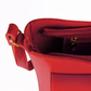 Red handbag with gold zipper and handle on a white background