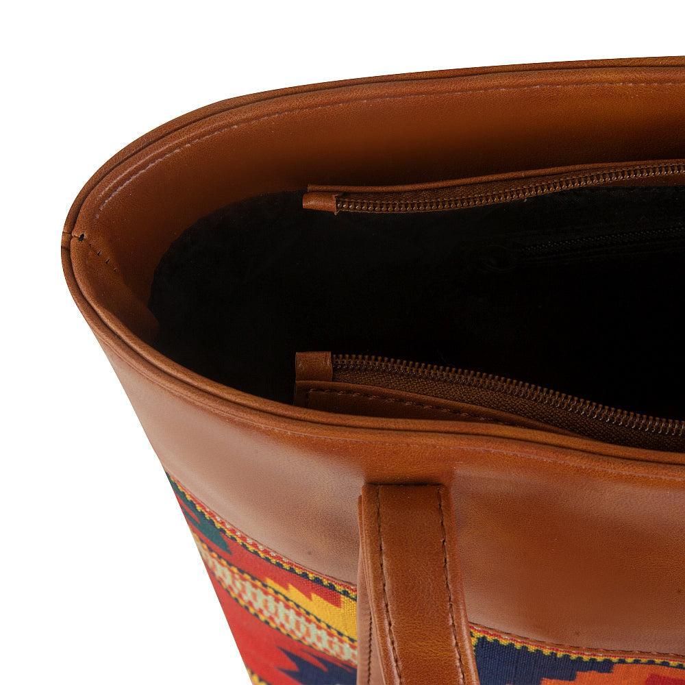 Brown leather bag with colorful patterned lining on a white background